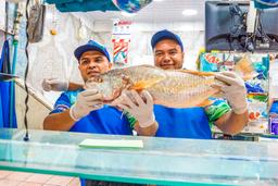 vip city tour men holding a fish at central market