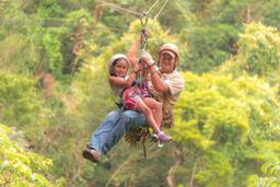 young girl riding with a guide tizati zip line rincon de la vieja