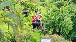 lady riding the cable with a guide above the resort los canones canopy tour la fortuna