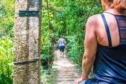 people crossing the celeste river hanging bridge