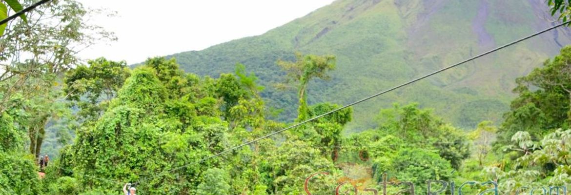tree platform a person zooming and arenal volcano as background los canones canopy tour la fortuna